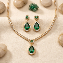 Conjunto de colar e brincos com pedra verde em formato de gota e cravejado.