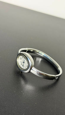 Relógio bracelete oval prata em aço inox com mostrador analógico e algarismos romanos.