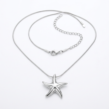 Colar de aço inox prata com pingente de estrela do mar, exibido em um busto de joias na cor bege.