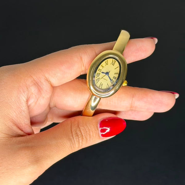 Relógio bracelete oval dourado com mostrador analógico da Amba Black.