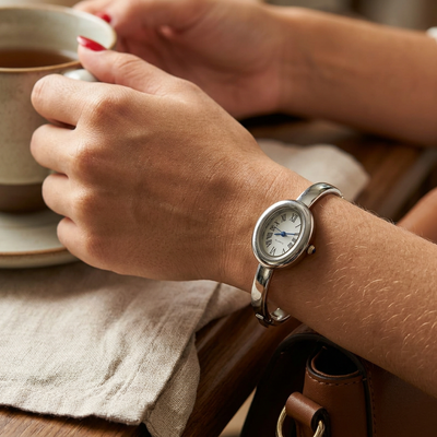 Relógio bracelete oval prata em aço inox com mostrador analógico e algarismos romanos.