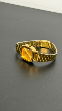 Relógio quadrado dourado com pulseira de aço inoxidável.