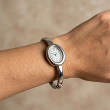 Relógio bracelete oval prata em aço inox com mostrador analógico e algarismos romanos.