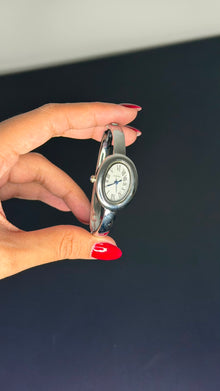 Relógio bracelete oval prata em aço inox com mostrador analógico e algarismos romanos.