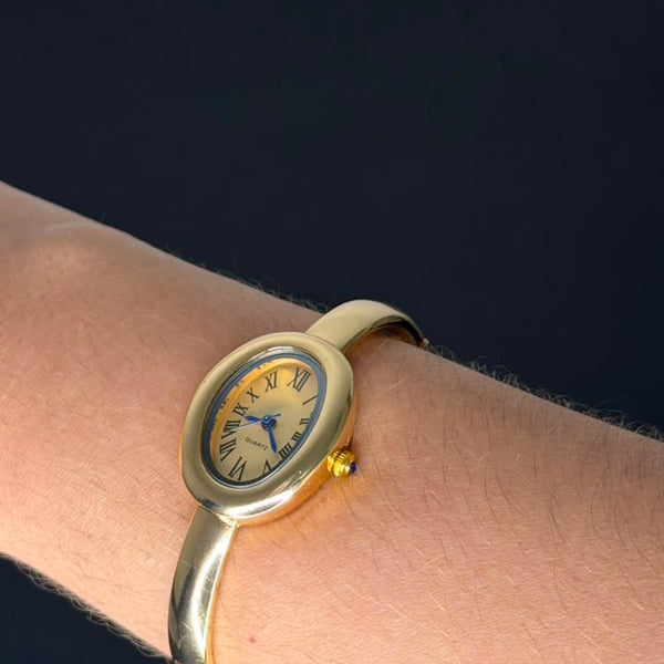 Relógio bracelete oval dourado com mostrador analógico da Amba Black.