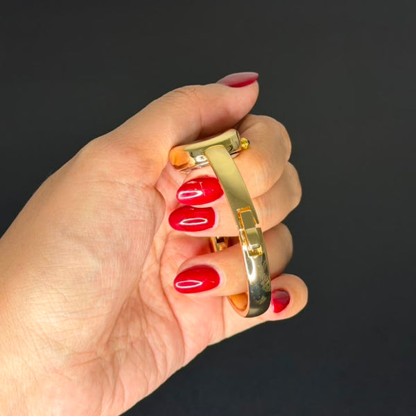 Relógio bracelete oval dourado com mostrador branco e números romanos.
