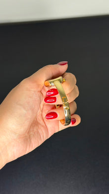 Relógio bracelete oval dourado com mostrador branco e números romanos.