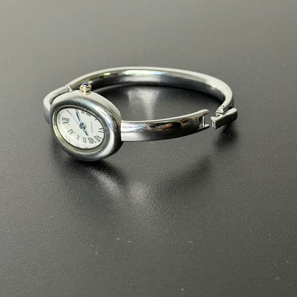 Relógio bracelete oval prata em aço inox com mostrador analógico e algarismos romanos.