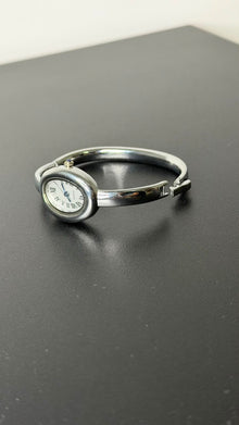 Relógio bracelete oval prata em aço inox com mostrador analógico e algarismos romanos.