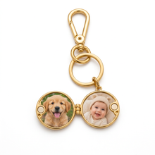 Chaveiro relicário redondo dourado com fotos de um cachorro e um bebê.