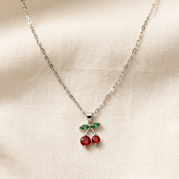 Colar com pingente de cereja em prata e detalhes vermelhos e verdes.