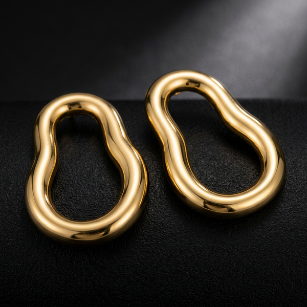 Brinco orgânico dourado em aço inoxidável sobre teclado.
