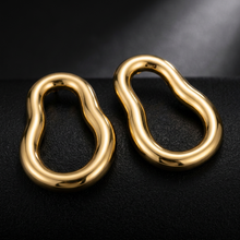 Brinco orgânico dourado em aço inoxidável sobre teclado.