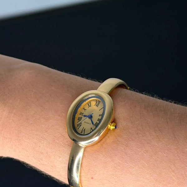 Relógio bracelete oval dourado com mostrador analógico da Amba Black.